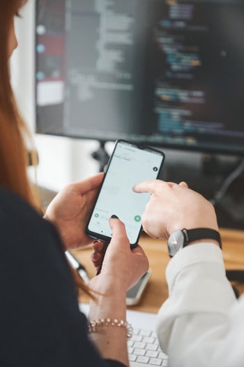 Personen zeigen auf Smartphone, wo die Hamwa-App geöffnet ist
