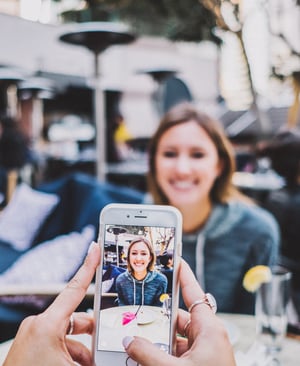 Kamera des Smartphones zeigt Frau an einem Tisch
