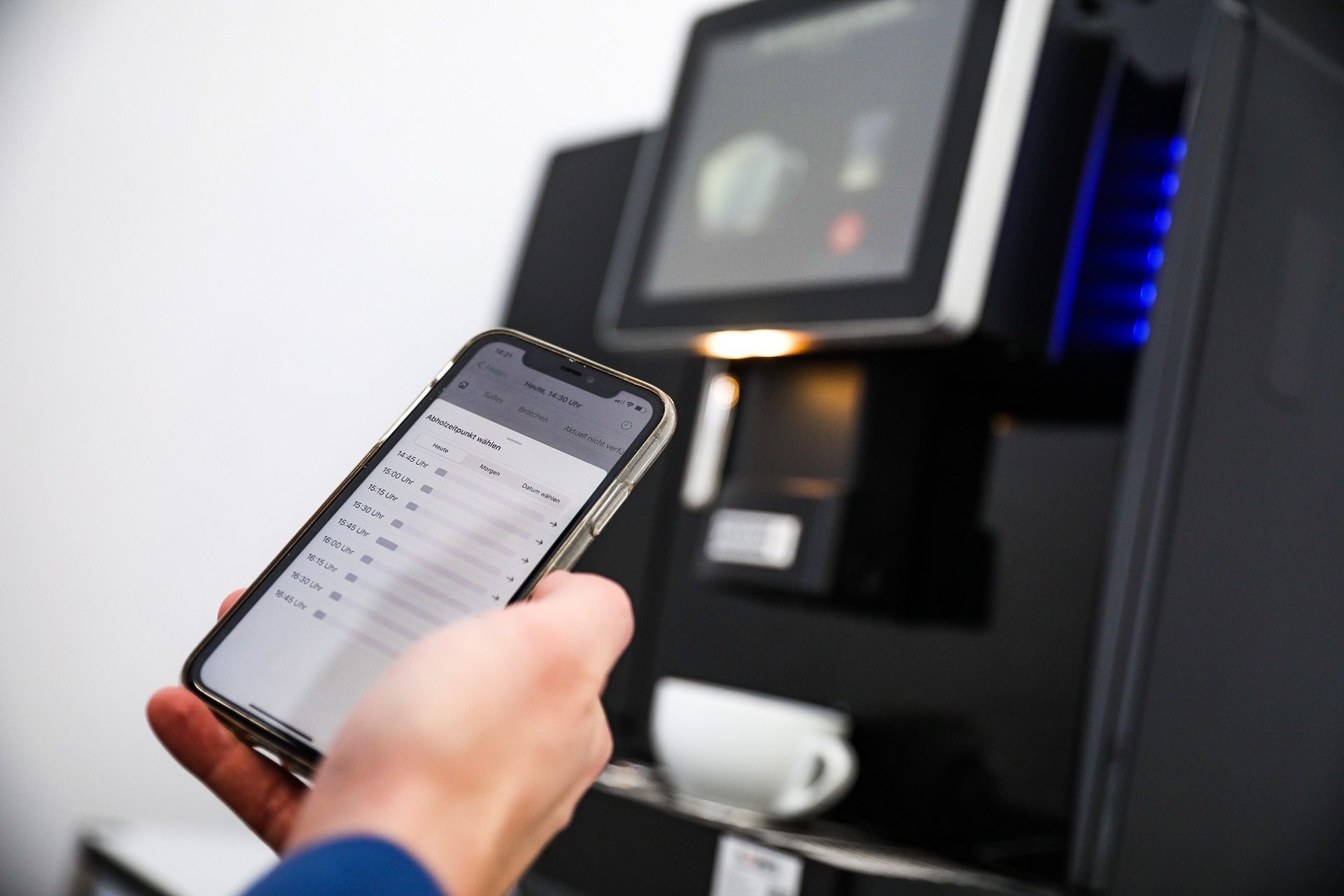 Smartphone vor Kaffeevollautomat